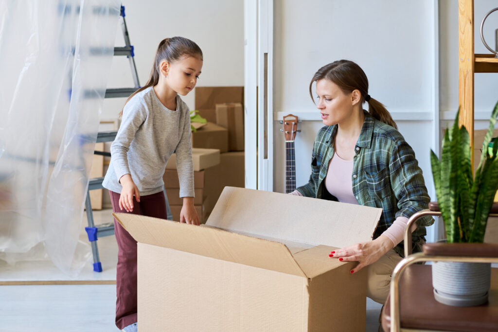 mother and child Unpacking box with household stuff